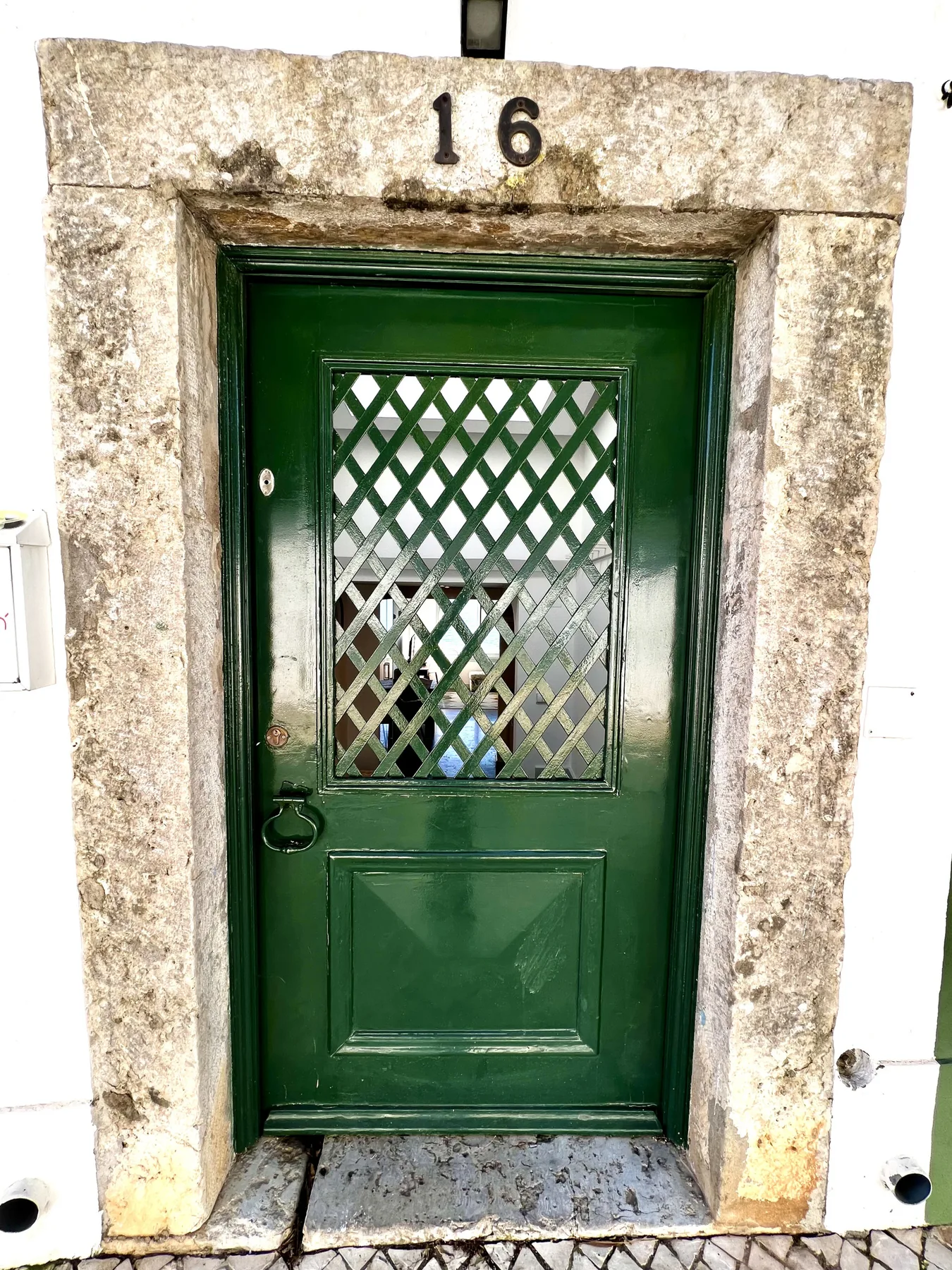 A dark green entrance door sits within a weathered stone doorway.
