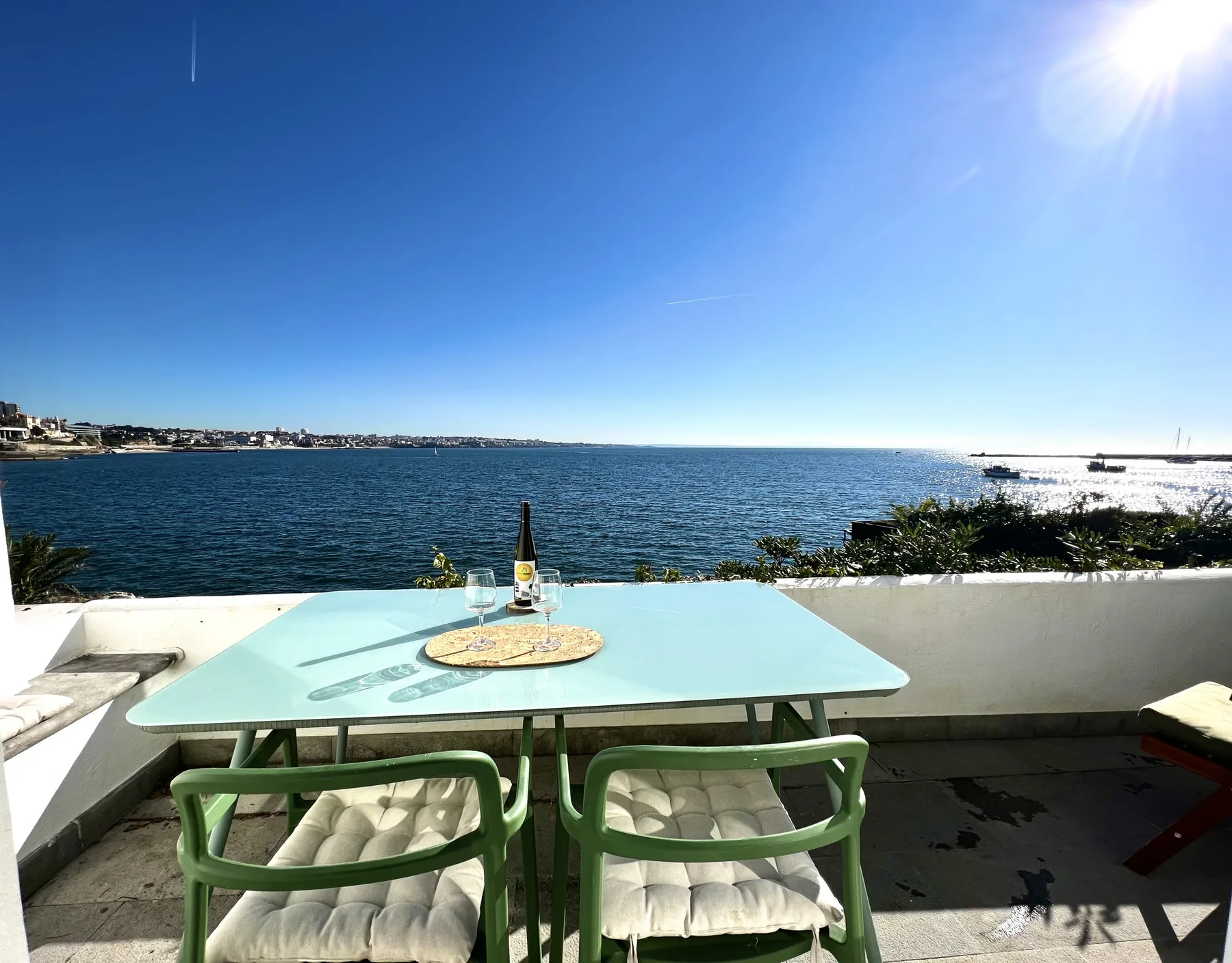 A seaside terrace with a table and seating overlooks the water.