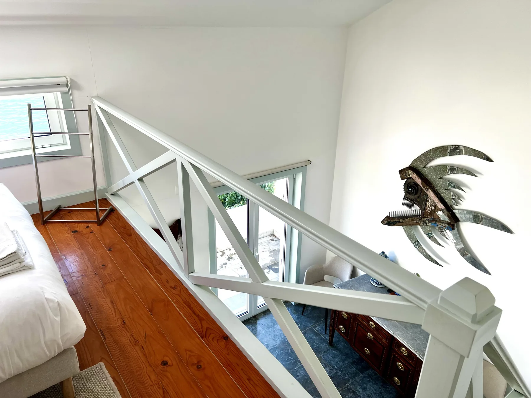 A bright loft bedroom overlooks a lower living area through a white railing.