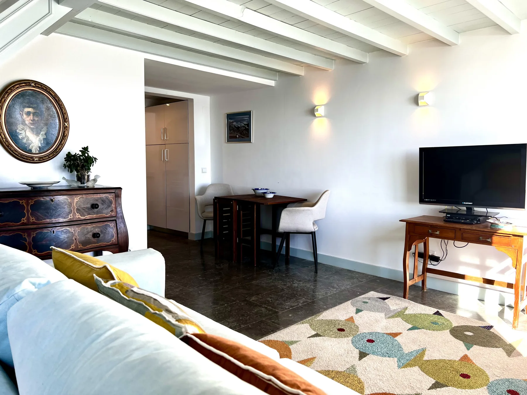 A bright living area with seating, a dining table, and a television.