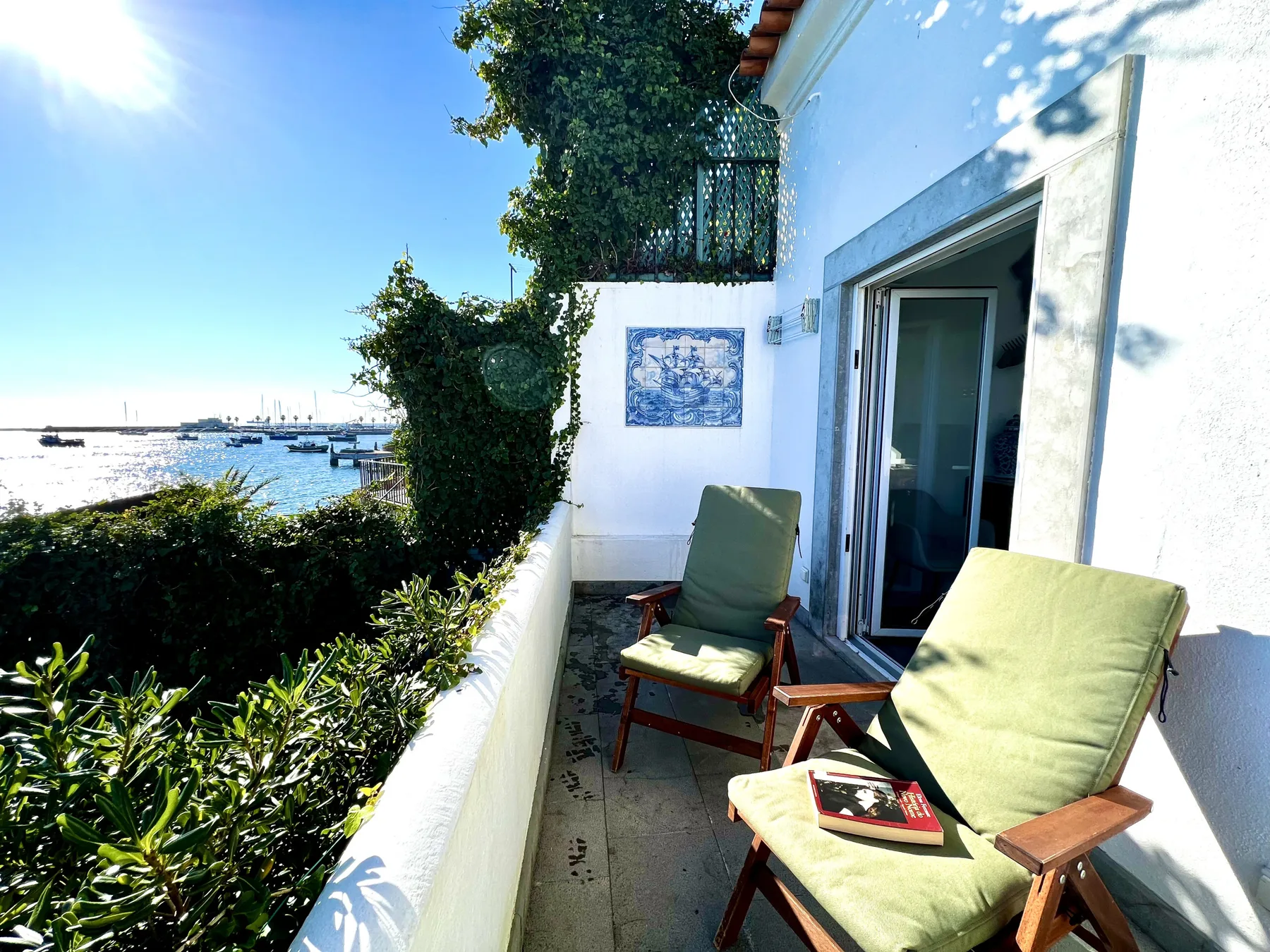 A sunny balcony with cushioned seating overlooks the water.