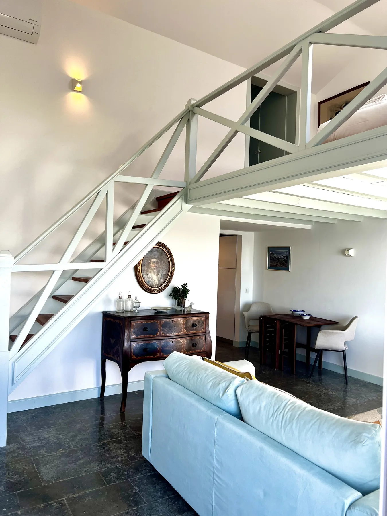 A living area with a staircase and seating beside a small dining table.