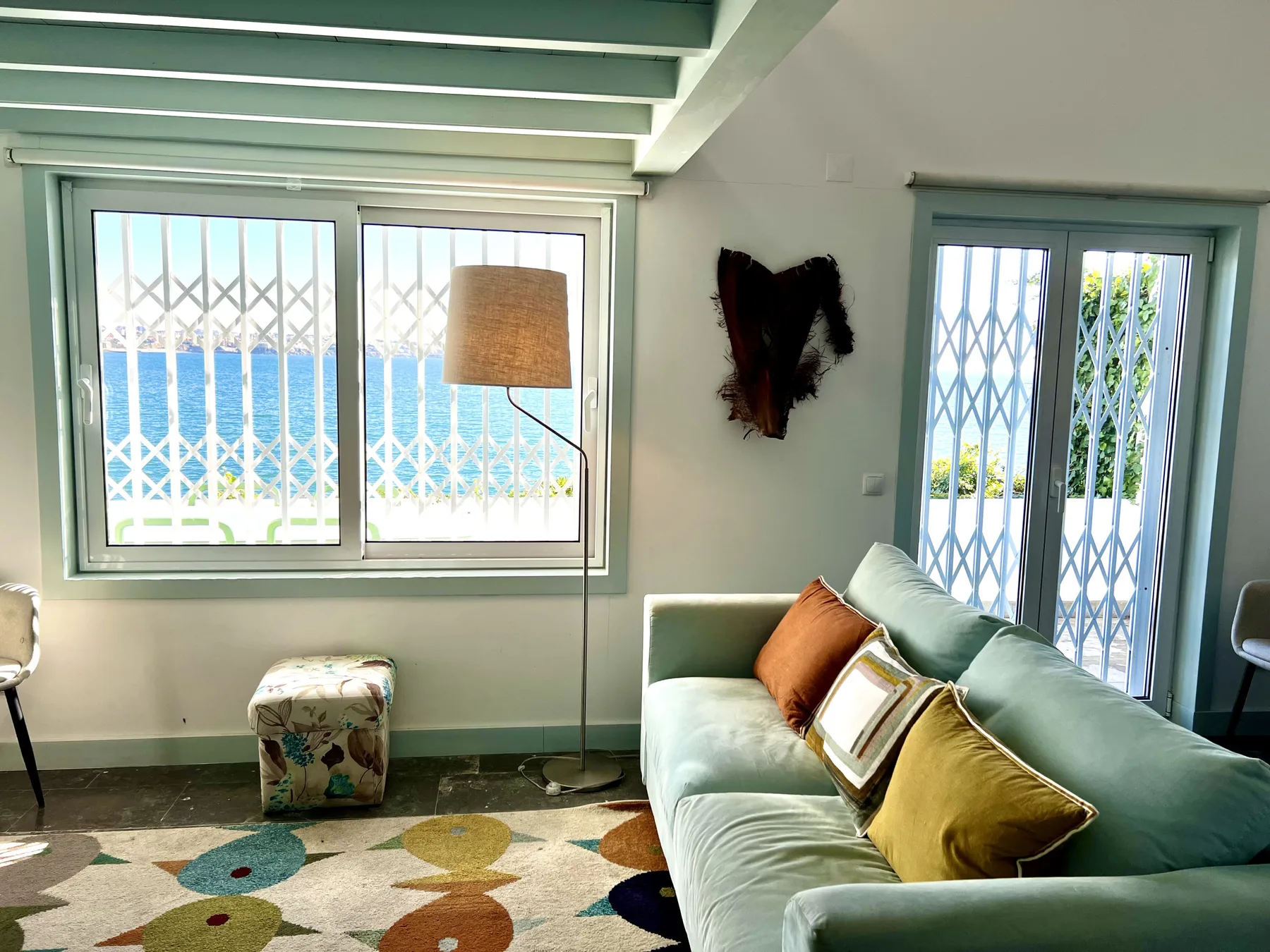 A bright living room with a pale green sofa beside large windows.