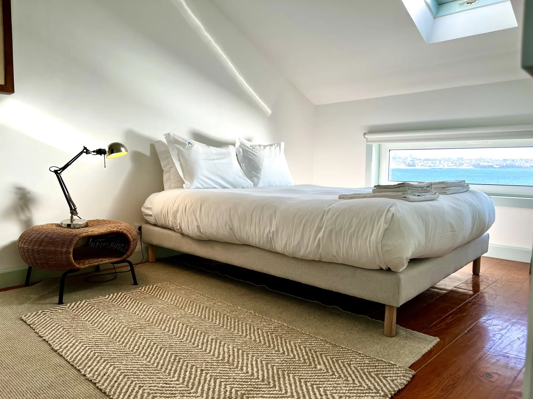 A bedroom with a low bed, a woven rug, and a window.