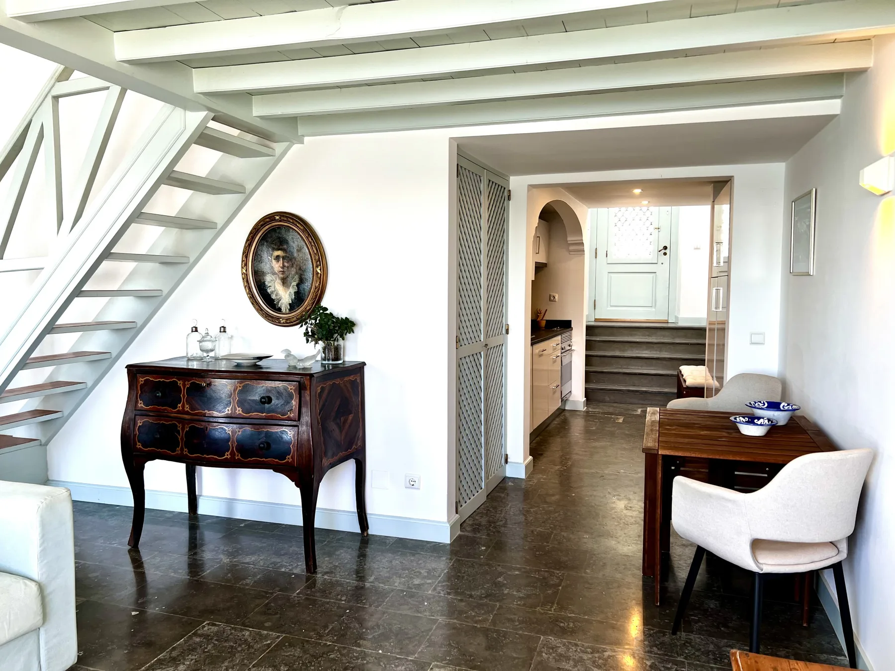 Interior hallway with a staircase, a wooden console table, and a small desk.