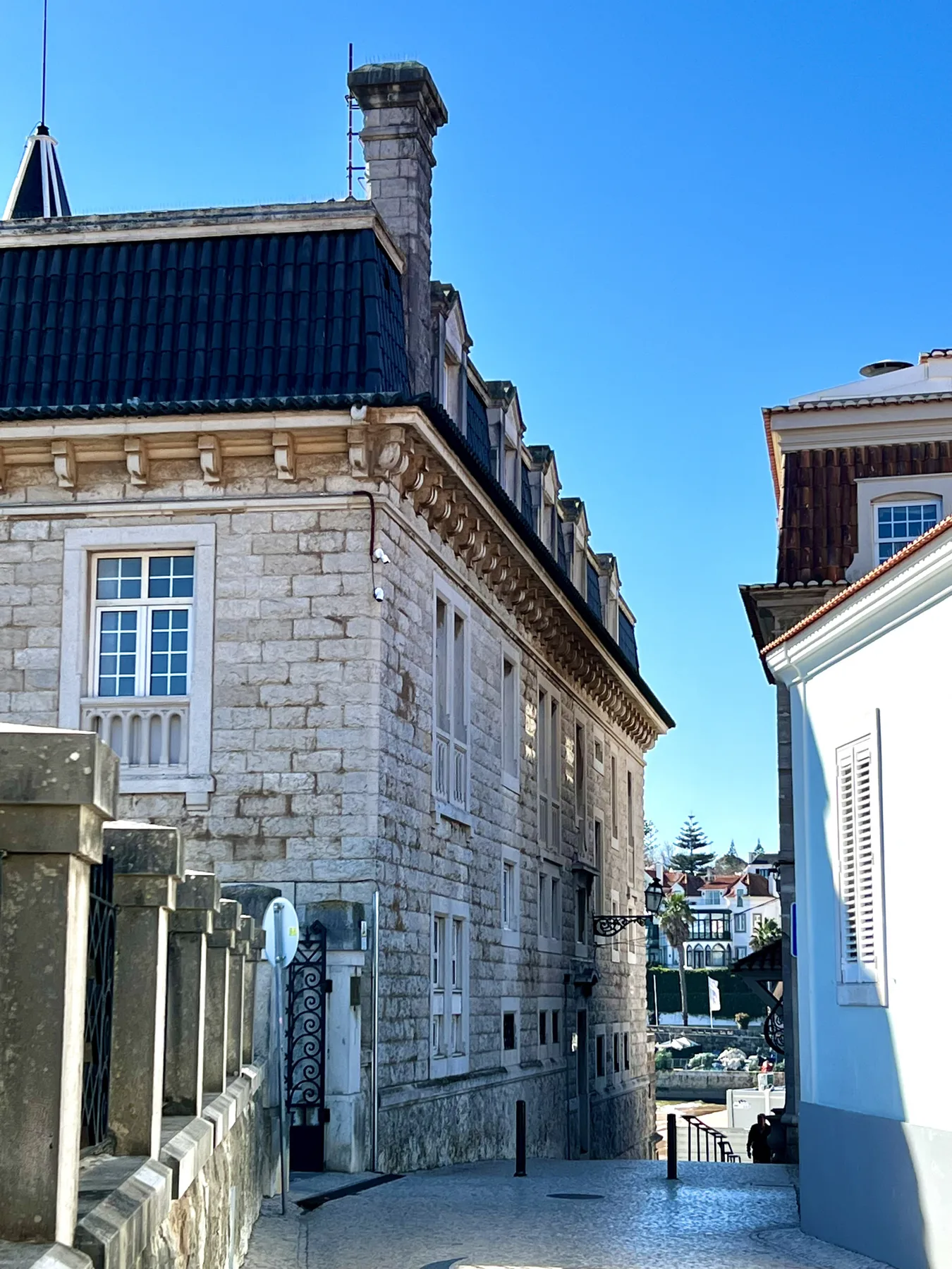 A narrow paved passage runs between stone and white buildings under a clear sky.