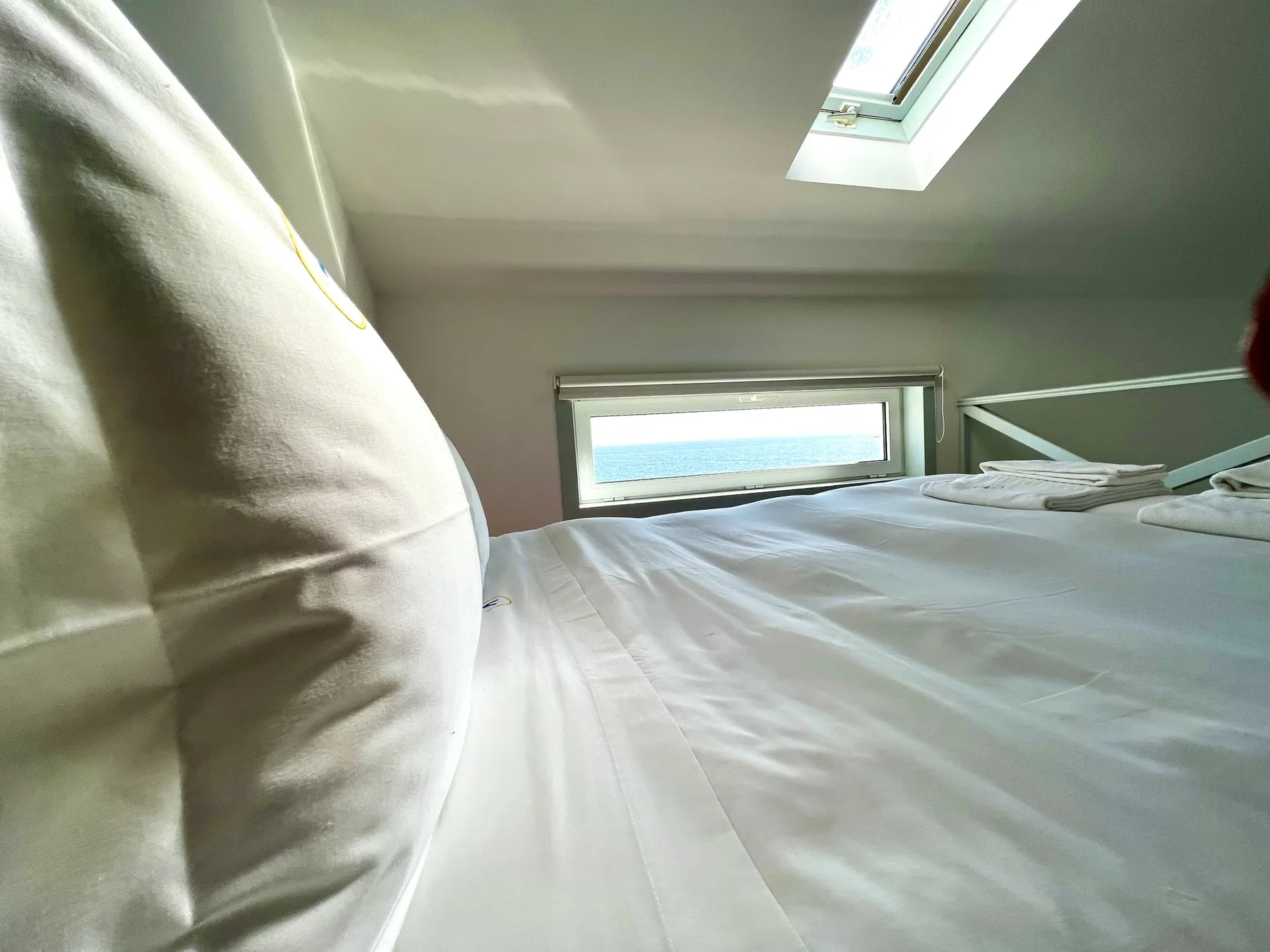 A bedroom with a low bed beneath a sloped ceiling and skylight.