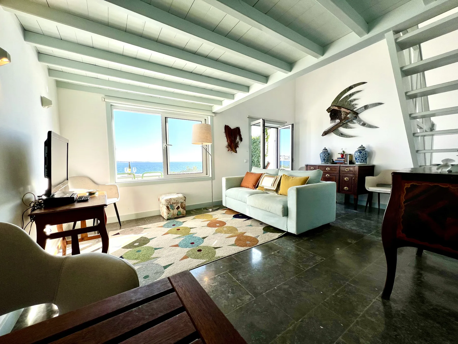A bright living room with seating, a rug, and large windows.