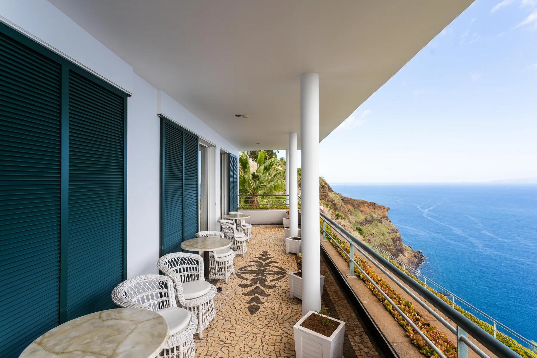 Un balcón cubierto con asientos al aire libre ofrece vistas al océano y a los acantilados.
