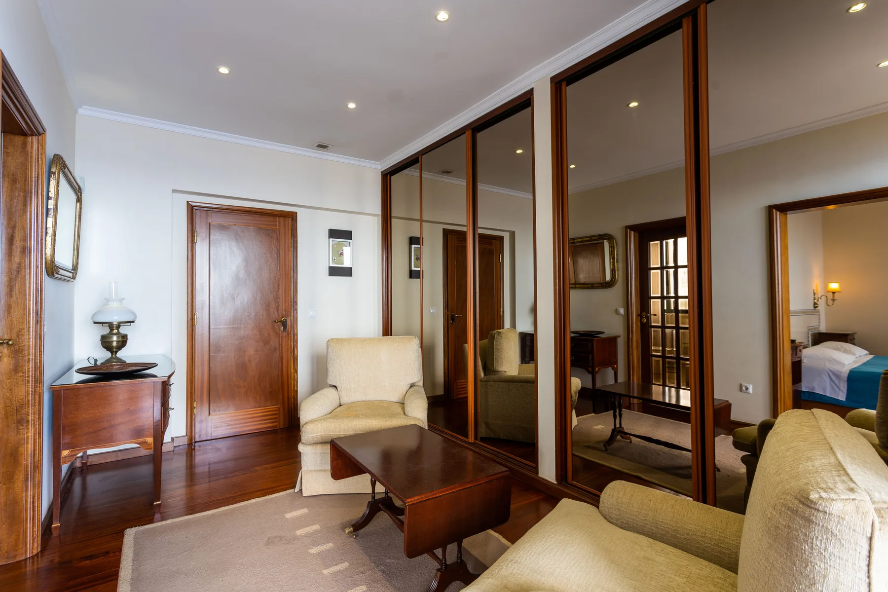 Una sala de estar con asientos tapizados, una mesa de centro y puertas de armario con espejo.