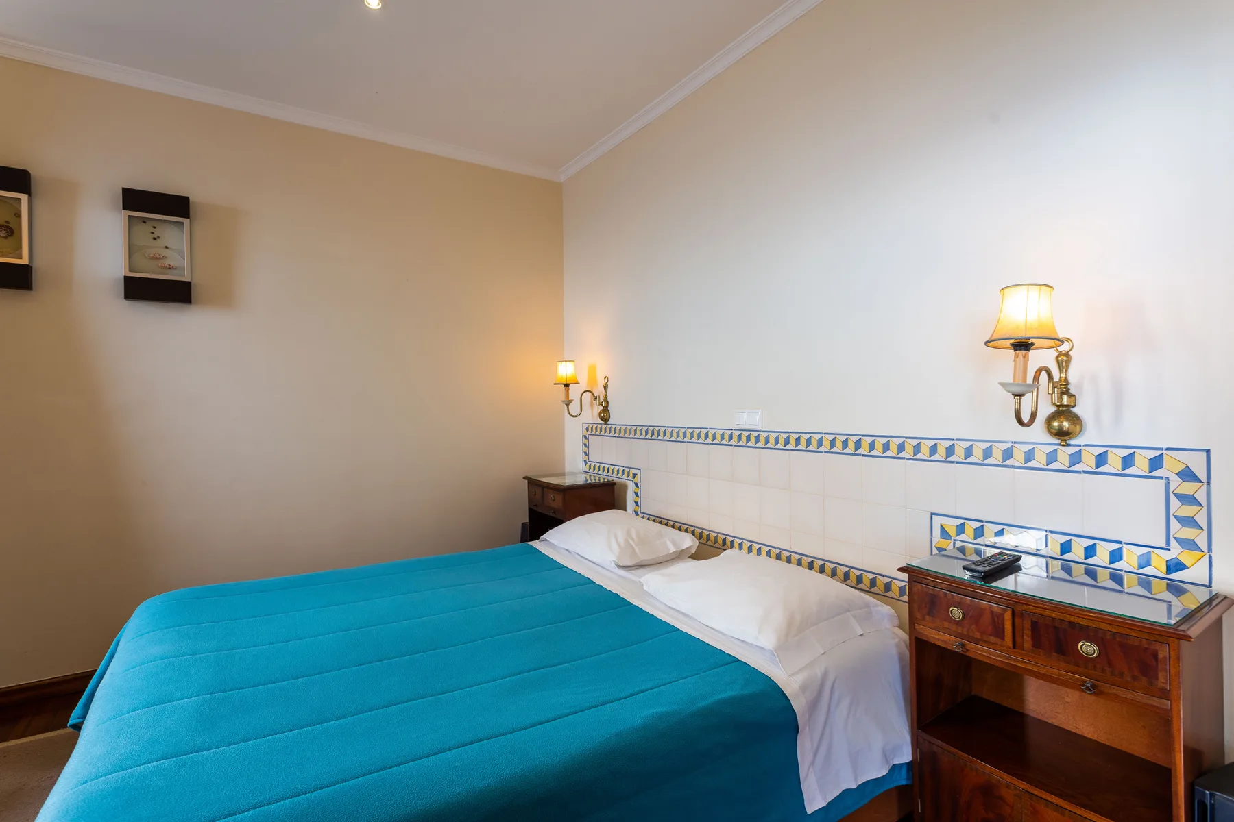 Un dormitorio con una cama cubierta con una colcha turquesa y mesillas de madera.