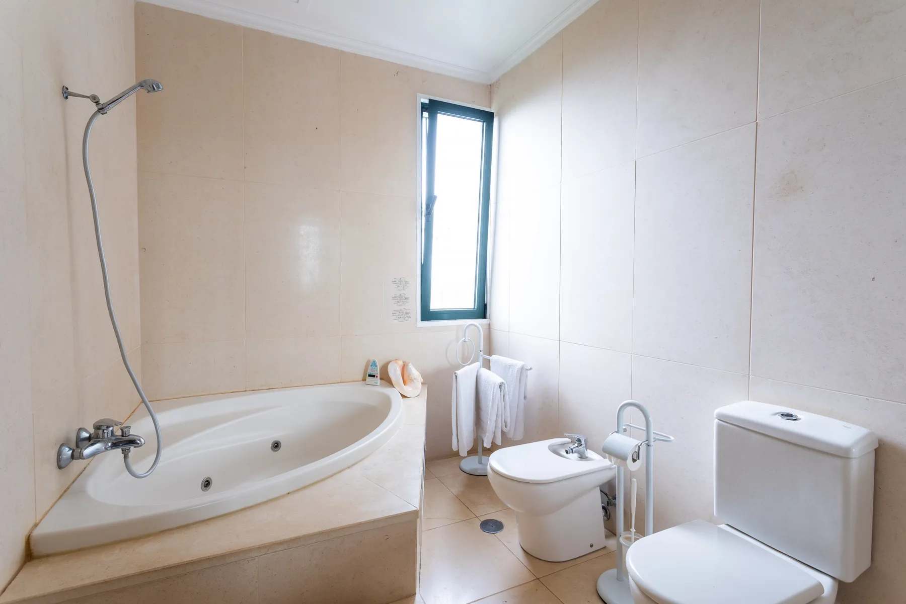 Un baño con bañera, inodoro y ventana.