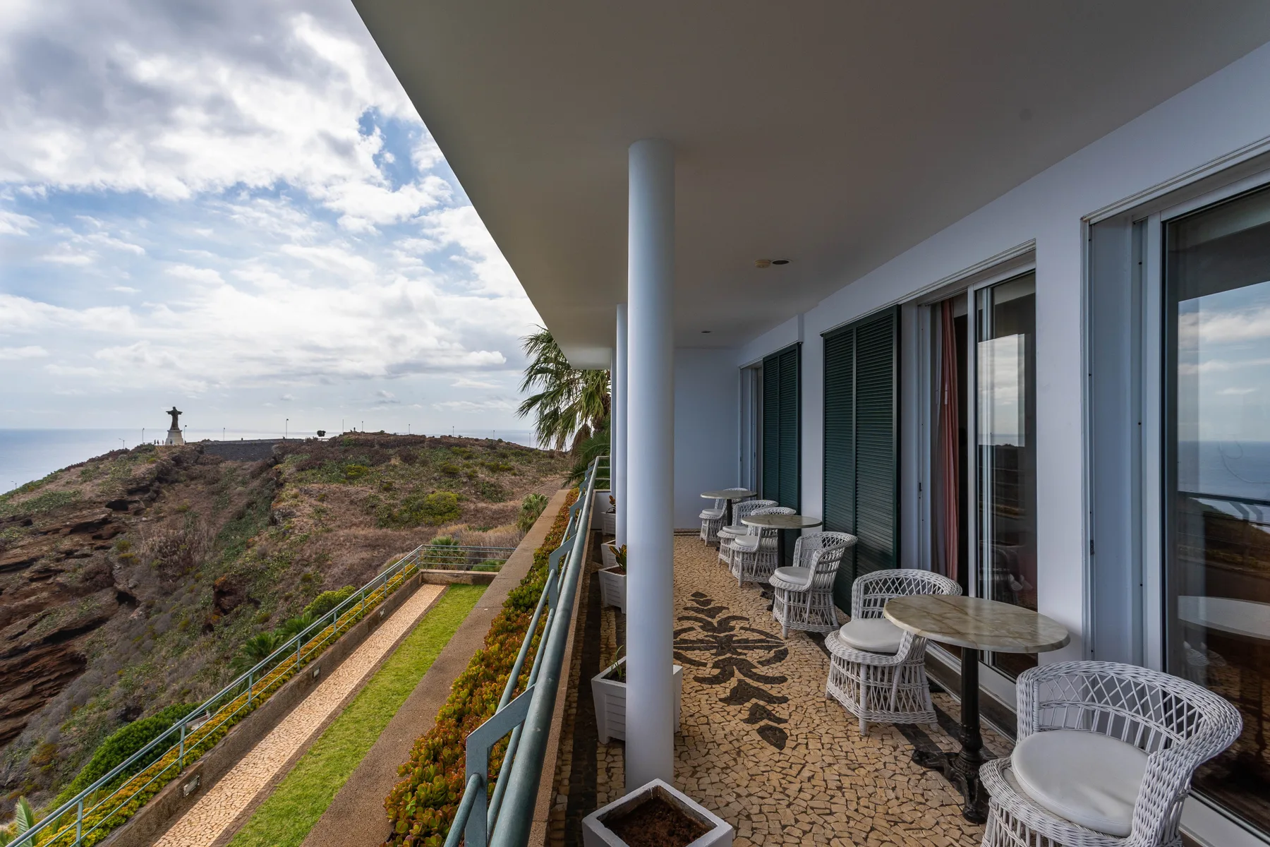 Una terraza cubierta tiene asientos al aire libre y vistas a una ladera.