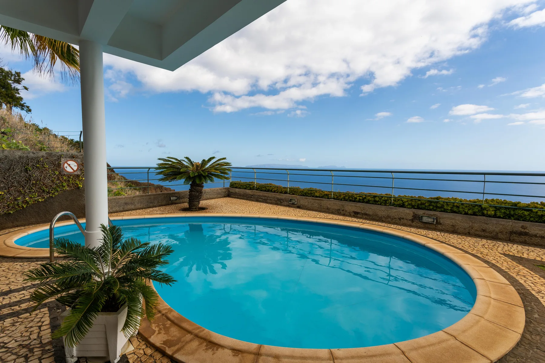 Una piscina curva ocupa una terraza con vistas al mar.