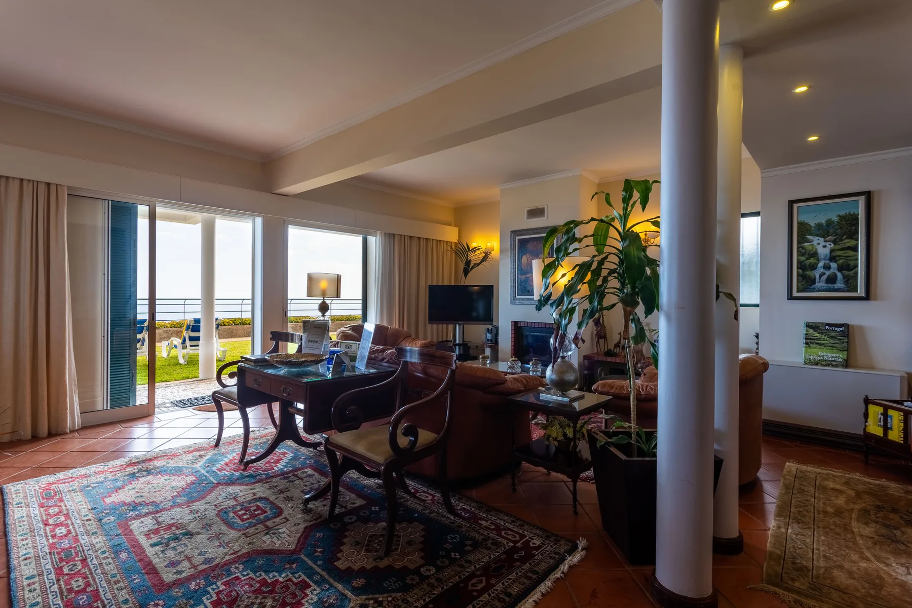 Sala de estar con asientos, una mesa de centro y puertas de vidrio que dan a un patio.