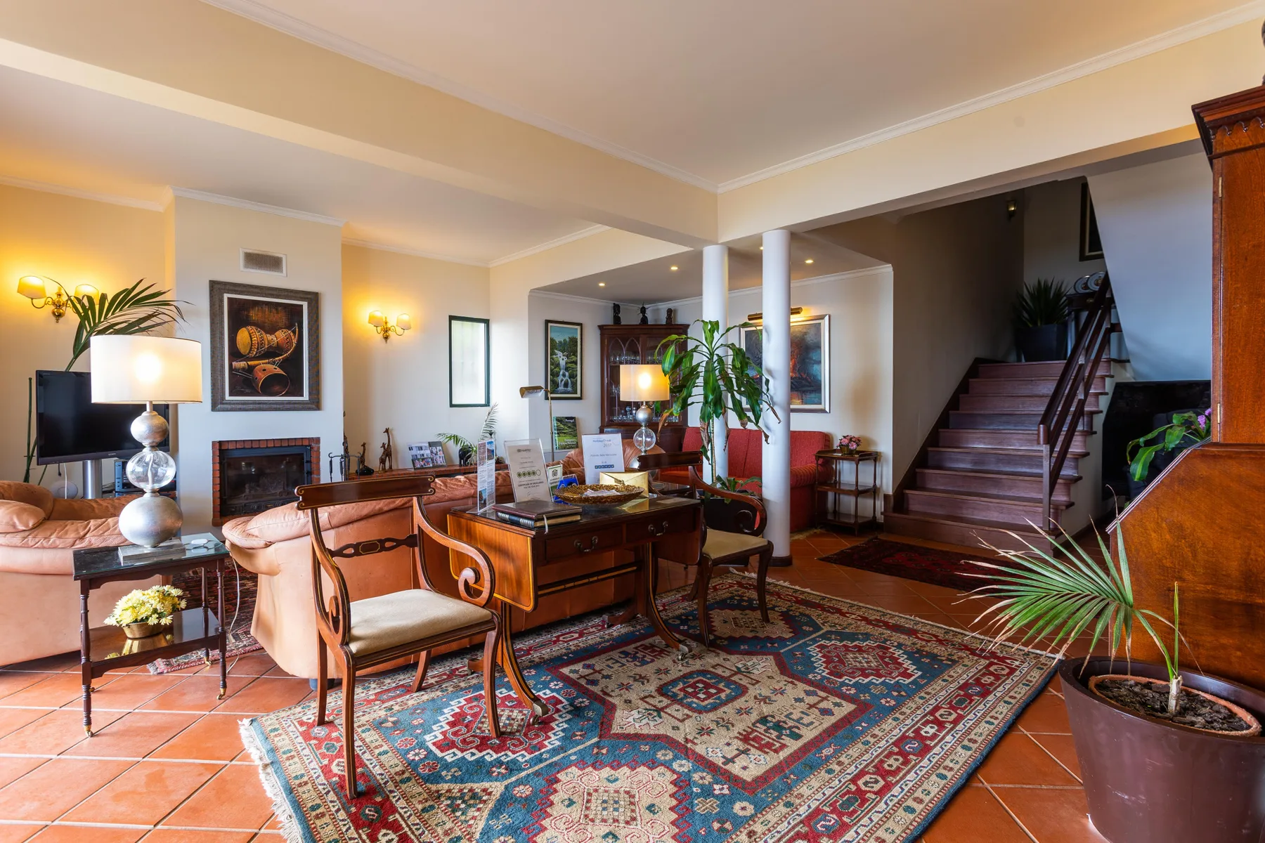 Una sala amueblada con asientos, una alfombra estampada y una escalera.
