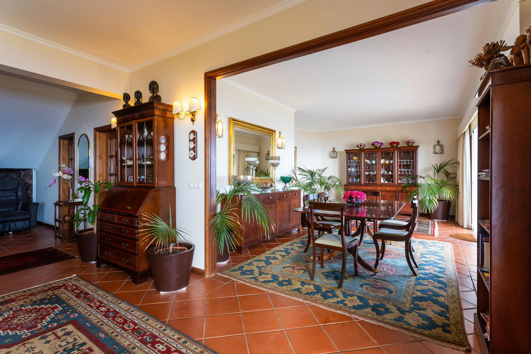 Comedor con una mesa y sillas, alfombras y armarios de madera.