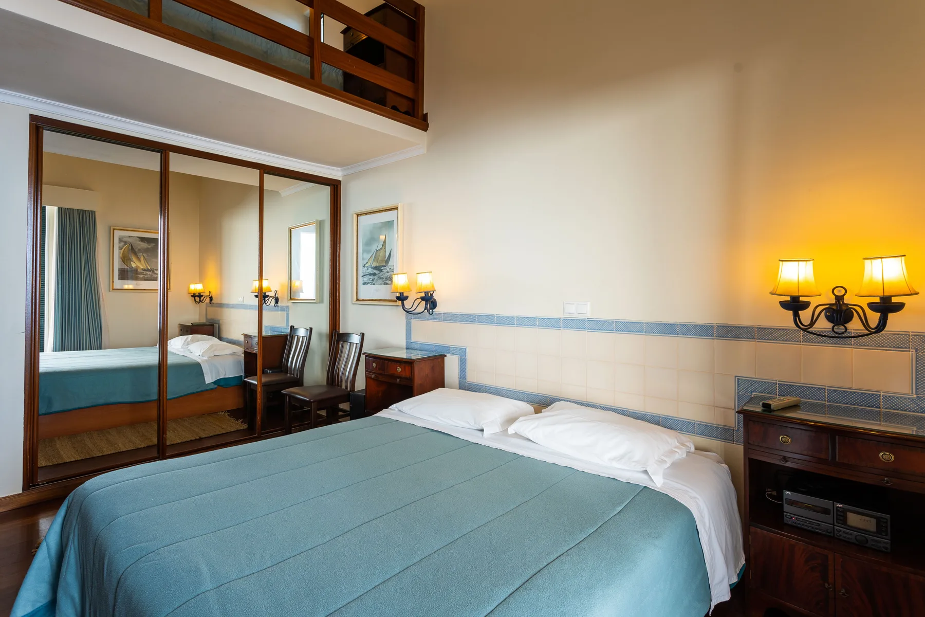 A bedroom with a large bed and mirrored wardrobe doors.