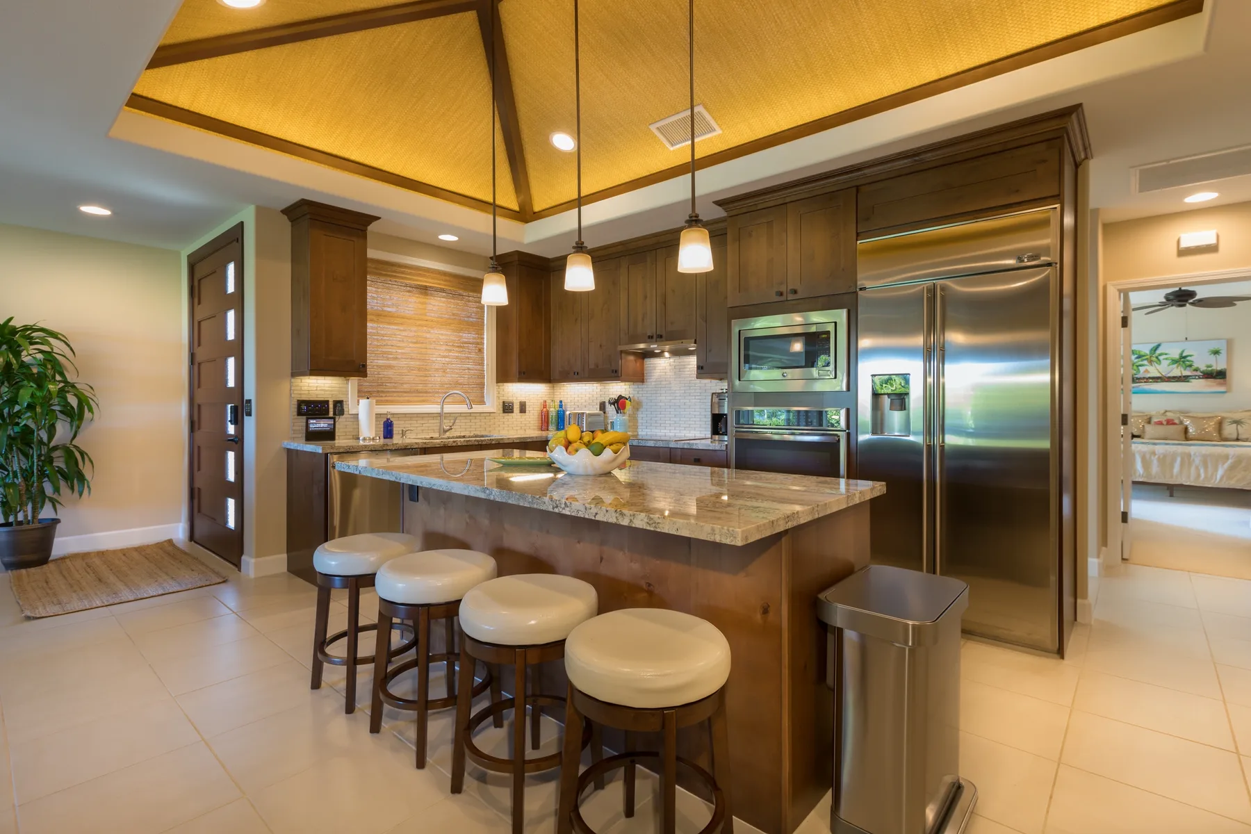 Una cocina con una isla central, asientos de barra y electrodomésticos de acero inoxidable.