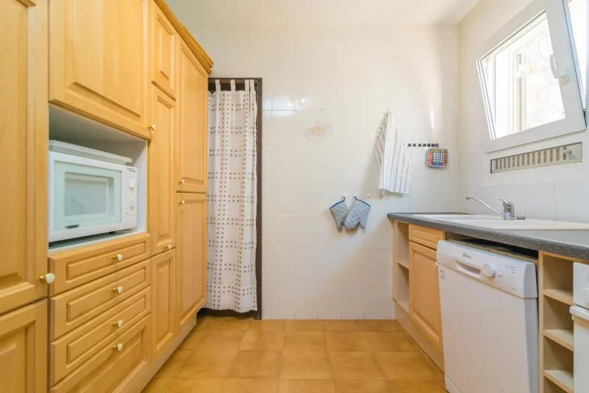 A kitchen with wooden cabinetry, a microwave, and a sink.