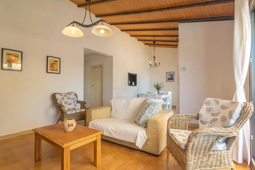 A living room with seating around a wooden coffee table beneath a beamed ceiling.