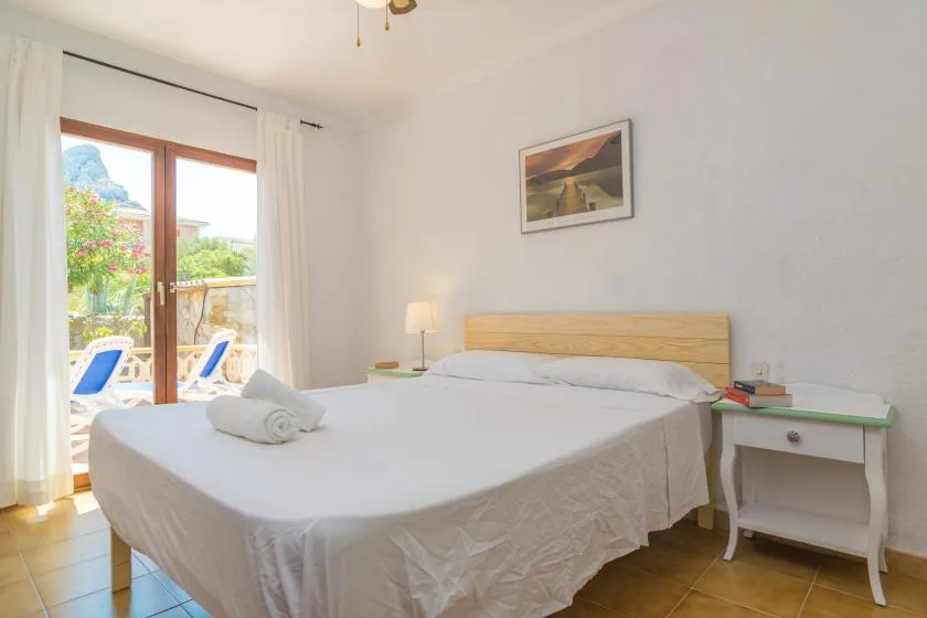 A bedroom with a large bed beside a glass door opening onto a patio.