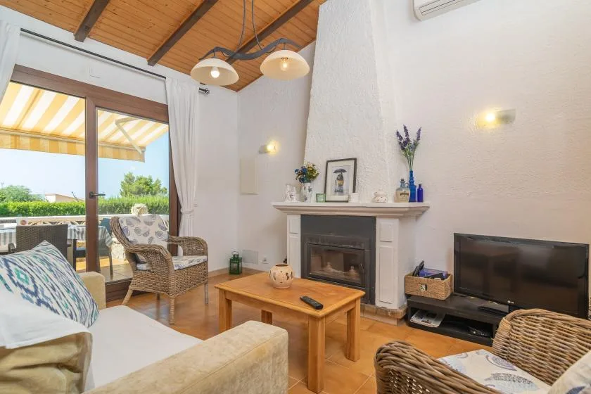 A bright living room with a fireplace, television, and seating beside a glass door.