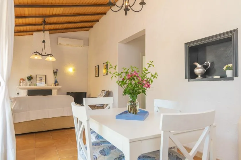 A dining area with a white table and chairs beside a living area.