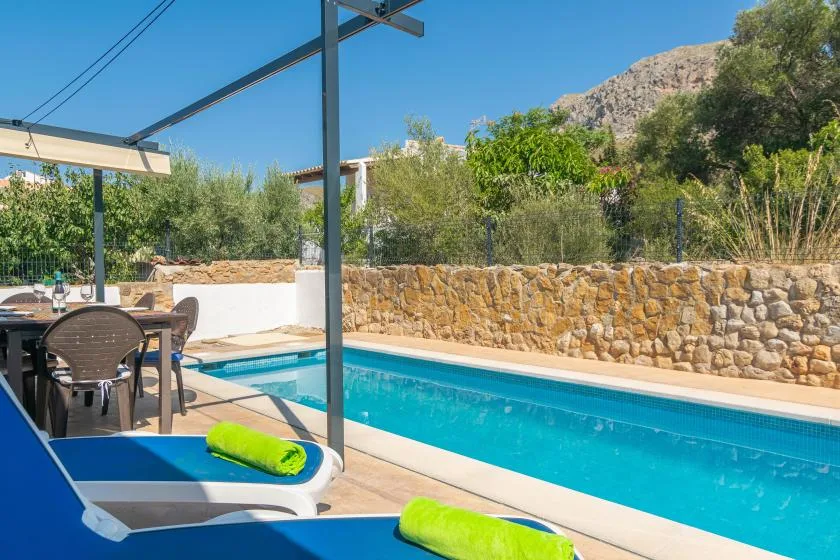 A swimming pool beside a shaded patio with outdoor seating.