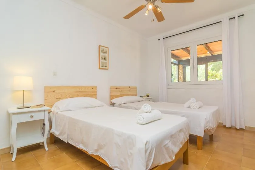 A bright bedroom with two beds, white linens, and a window.