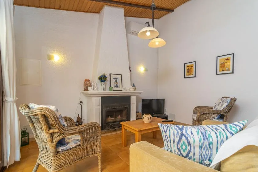 A living room with wicker seating, a fireplace, and a wooden coffee table.