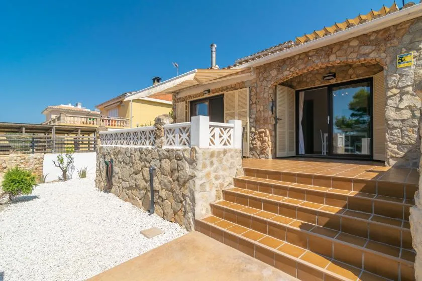 Stone house entrance with tiled steps leading to a glass patio door.