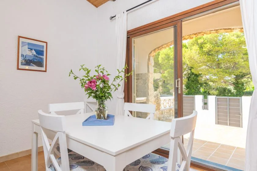 A bright dining area with a white table beside glass doors opening to a patio.