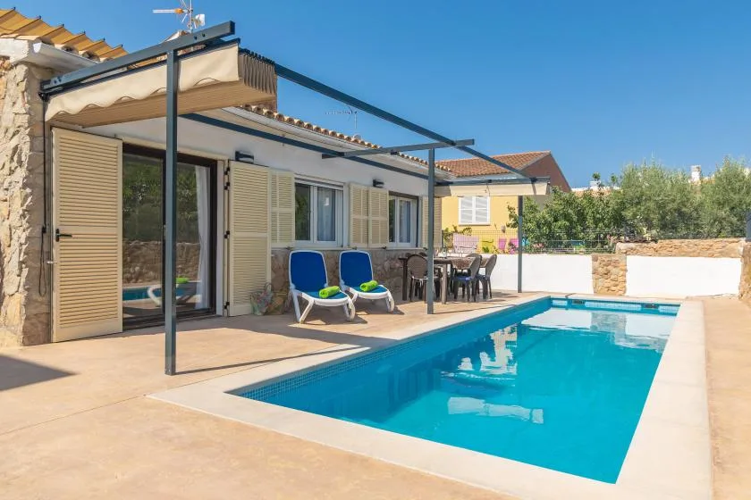 A swimming pool beside a house, with lounge seating on the patio.