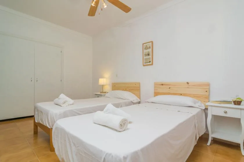 A bright bedroom with two neatly made beds and a small bedside table.