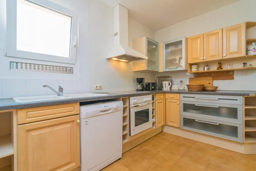 A bright kitchen with wooden cabinets, a countertop, and built-in appliances.