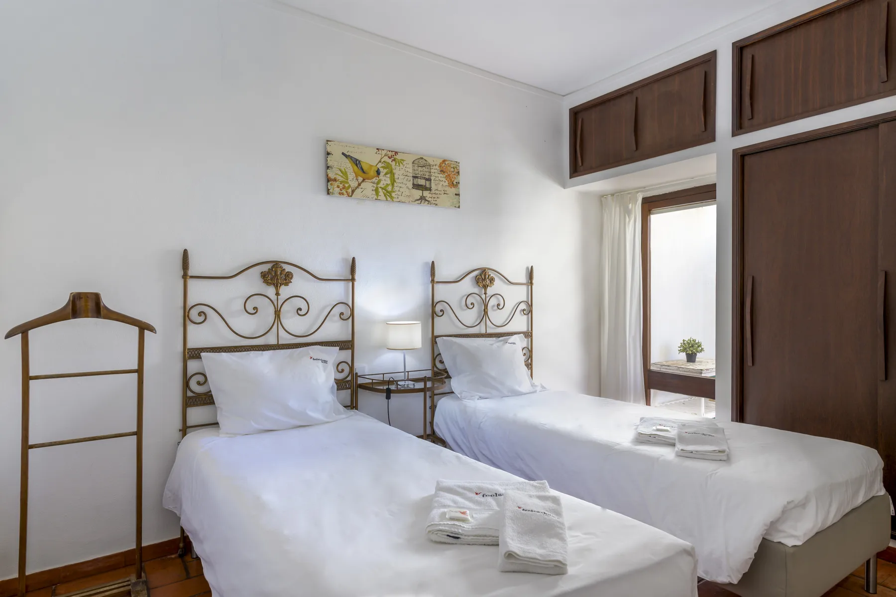 A bedroom with two beds, white linens, and dark wood cabinets.