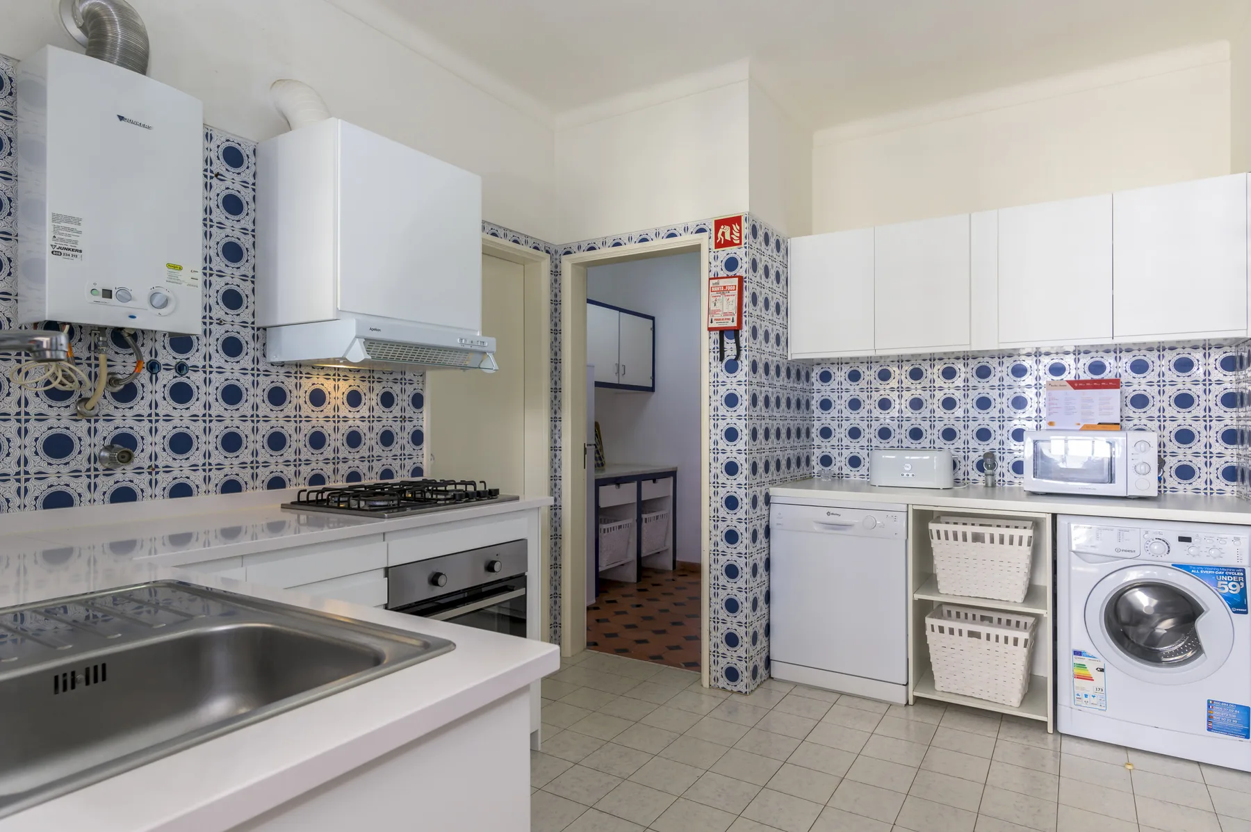A tiled kitchen with a sink, stovetop, and washing machine.