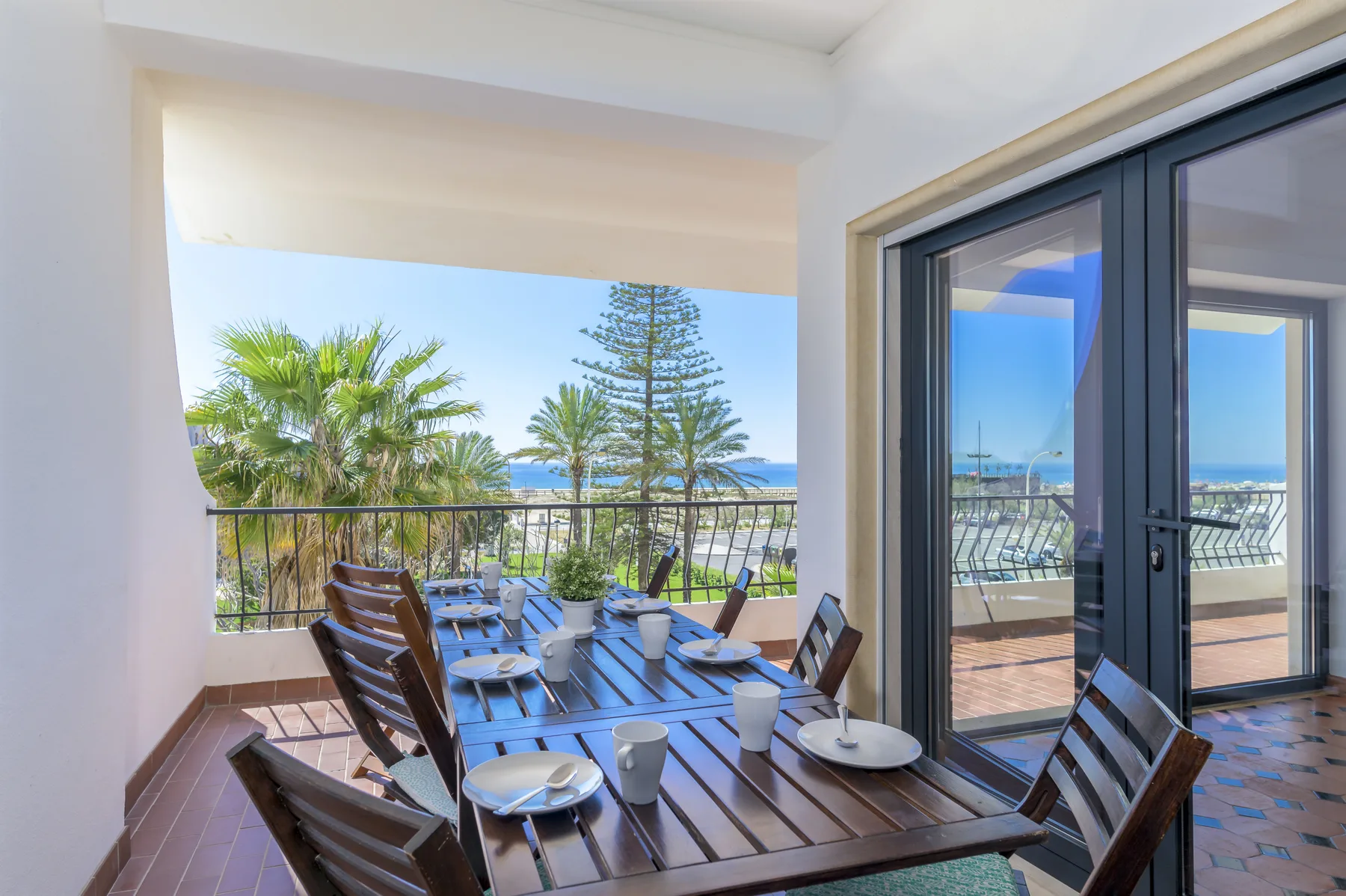 A balcony dining area with a table and seating overlooking the sea.