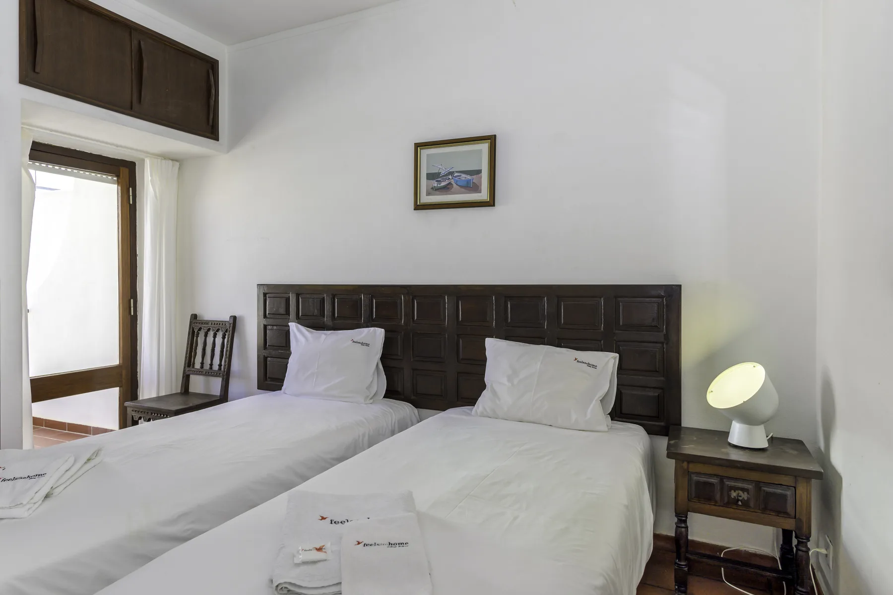 A bedroom with two single beds and a dark wooden headboard.