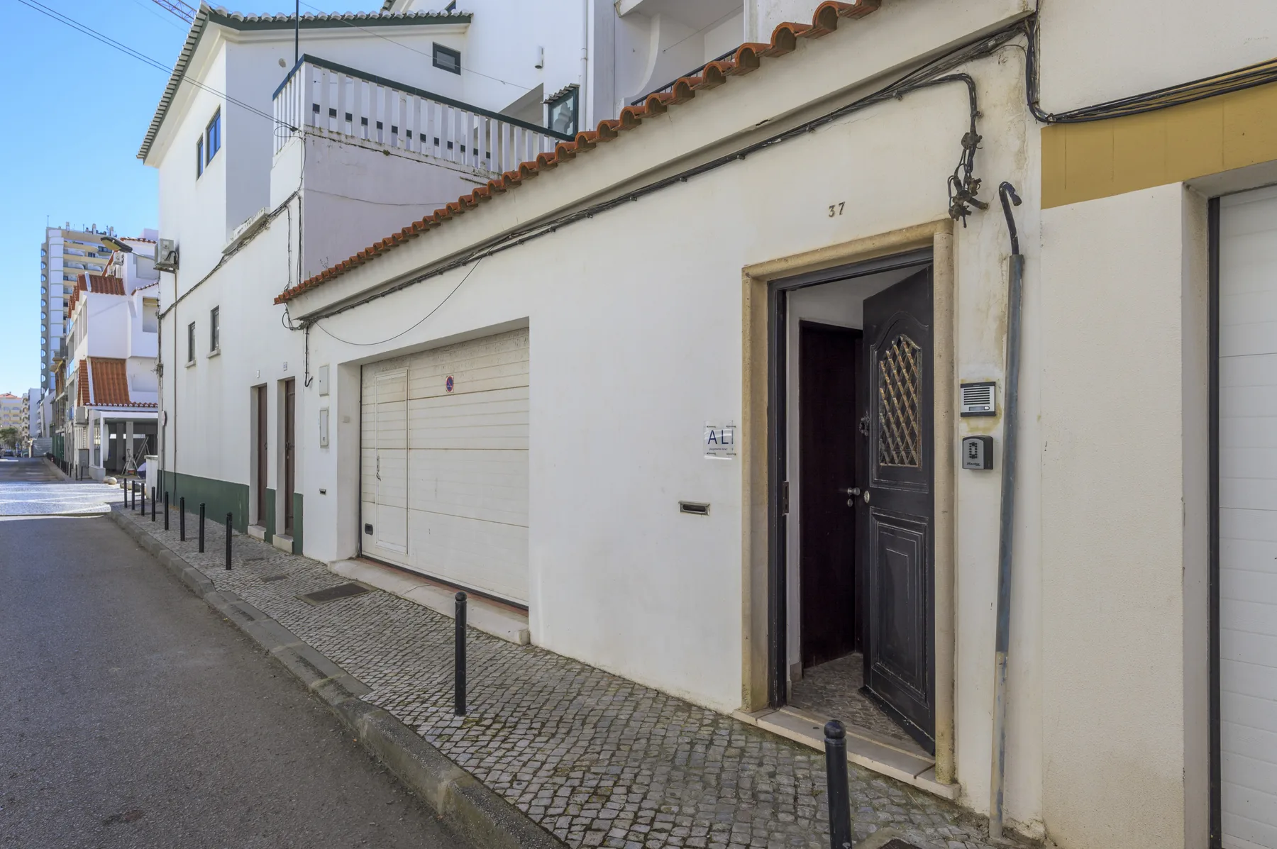 Street view of a white building with an open doorway and garage door.