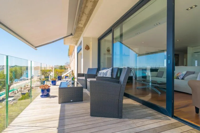 A balcony seating area with glass railings and sliding doors.