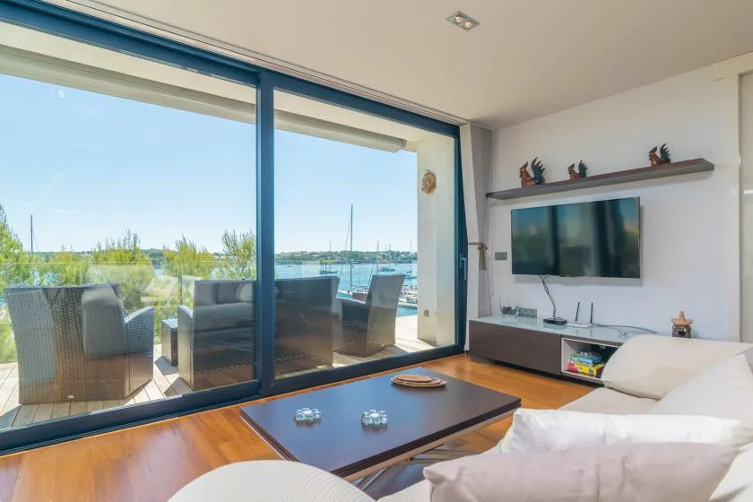 A living room with seating beside large windows overlooking the water.