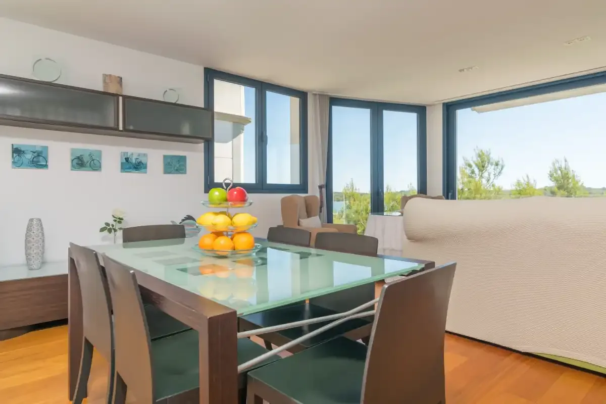 A dining area with a glass table and large windows.