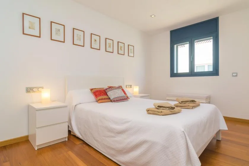 A bright bedroom with a neatly made bed and framed pictures on the wall.