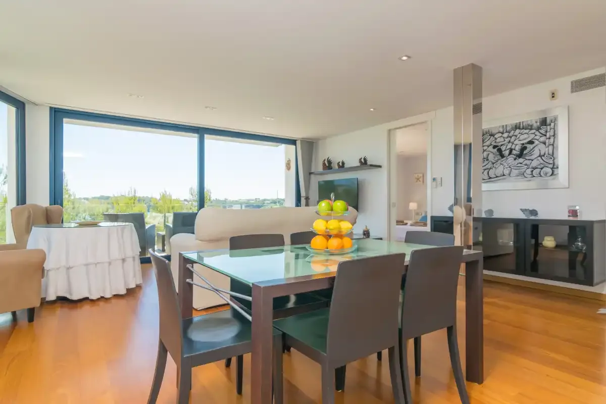 A dining area with dark seating and large windows overlooking greenery.