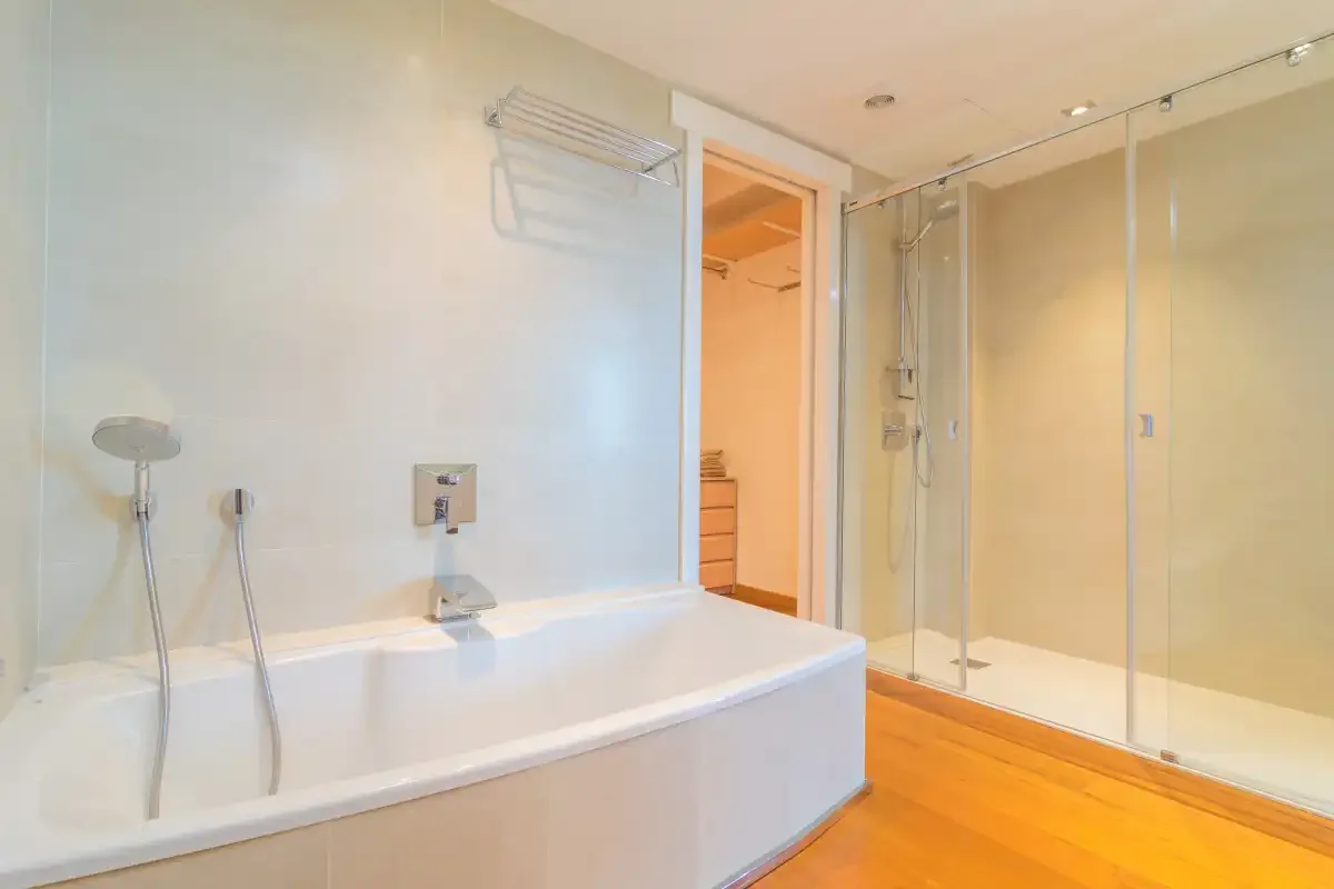 A bright bathroom with a bathtub and glass-enclosed shower.