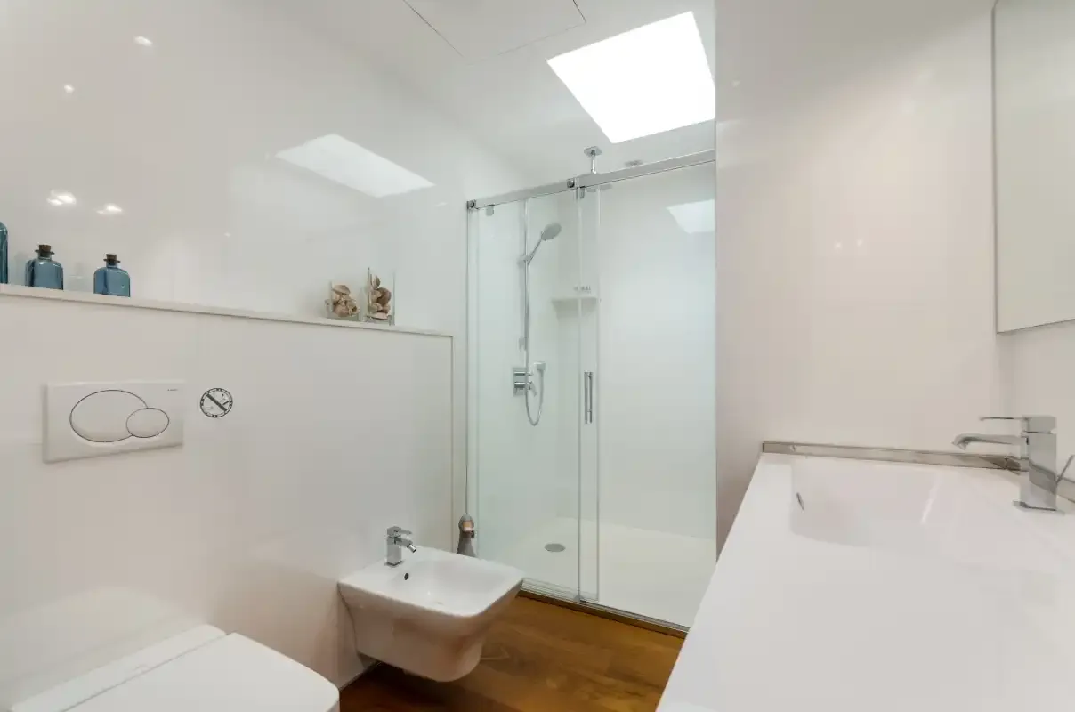 A bright bathroom with a glass shower and white sink.