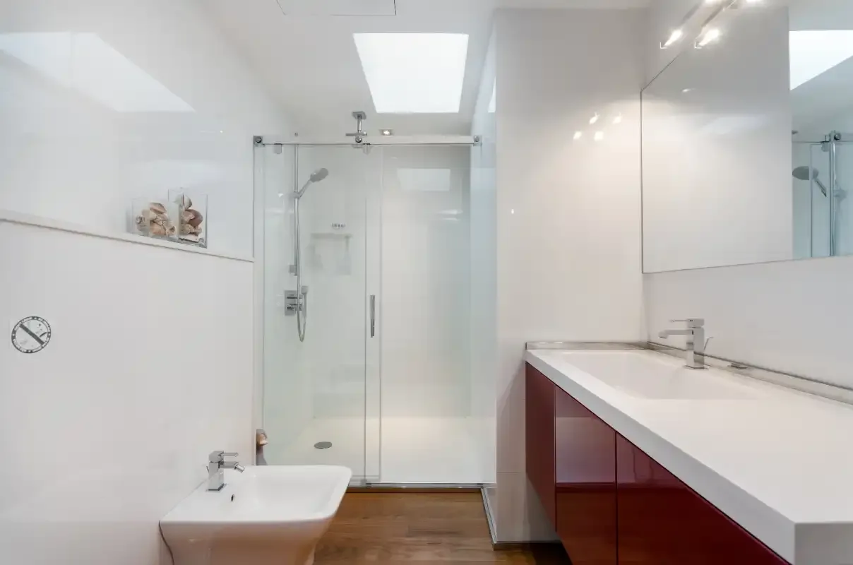 A bright bathroom with a glass-enclosed shower and a long vanity.