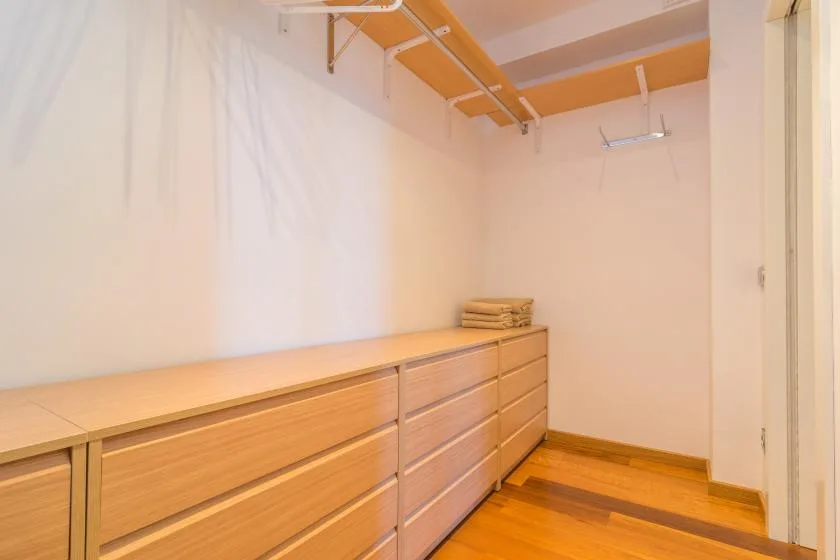 A walk-in closet with built-in drawers and overhead clothing rails.